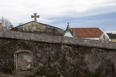 Cross on cemetery against cloudy sky