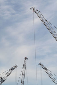 Low angle view of cranes against sky