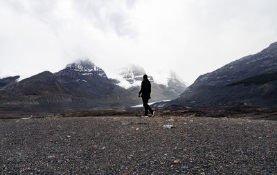 Lone man walks in dramatic mountain peaks