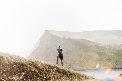 Rear view of man walking on mountain against clear sky