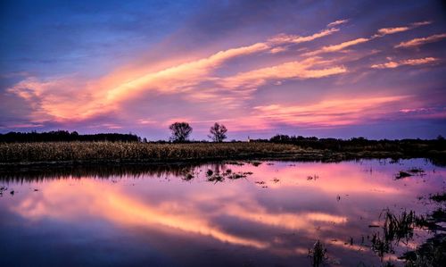 Scenic view of lake against dramatic sky during sunset