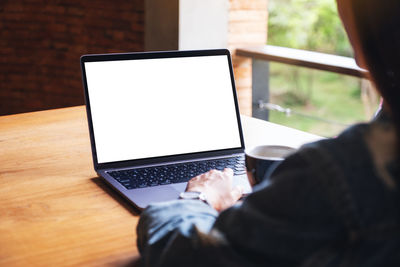 Midsection of woman using laptop at table