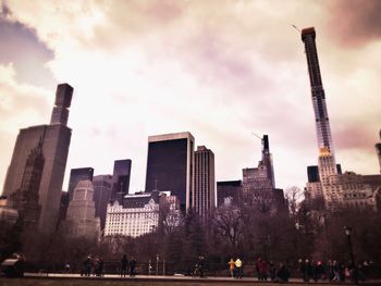 People on city buildings against cloudy sky