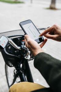 Close-up of man with e-bikeusing smartphone navigation system