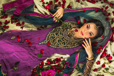 Woman wearing indian traditional cloth laying on the ground with romantic set , top view