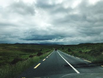 Road passing through landscape against cloudy sky