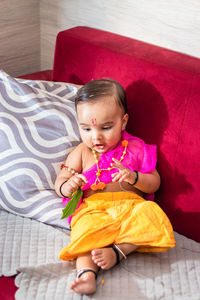 Cute indian boy dresses as lord rama with bow and flowers from top angle