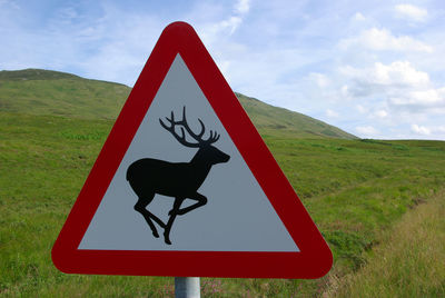 Close-up of road sign on landscape against sky