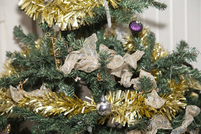 Golden tinsel wrapped around an artificial tree with  ribbon,  globes,  and  star decorations