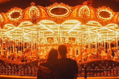 Rear view of couple kissing illuminated at night