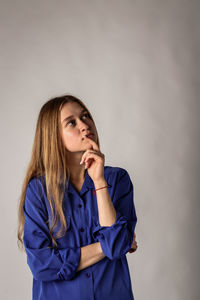 Portrait of young woman standing against wall