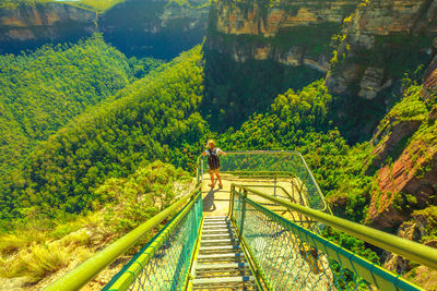 High angle view of woman standing by railing by mountains over trees