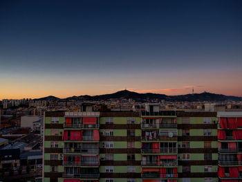 Buildings in city against clear sky during sunset