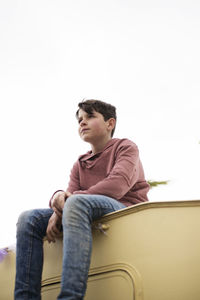 Low view of a young boy sitting on the top of a caravan