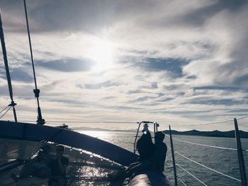 Low section of woman on sea against sky during sunset