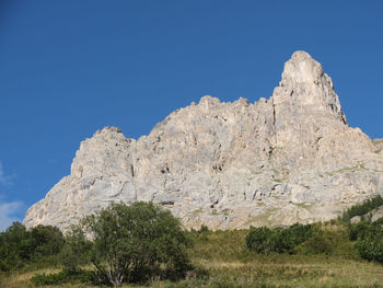 Low angle view of rocks against clear blue sky