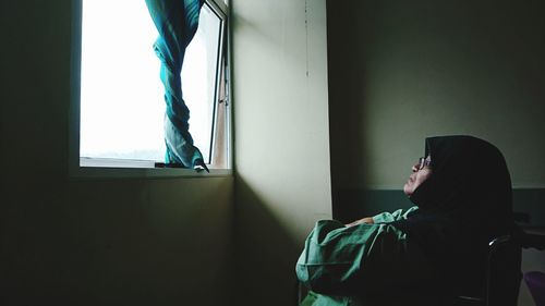 Woman looking through window at home