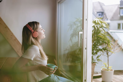 Young woman relaxing at home with a cup of tea, listening music