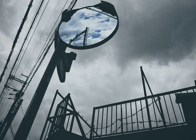 Low angle view of metallic structure against cloudy sky