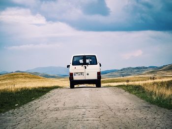 Road amidst field against sky