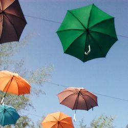 Close-up of multi colored umbrellas hanging against sky