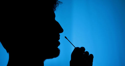 Silhouette of a man making his own self-swab test covid at home