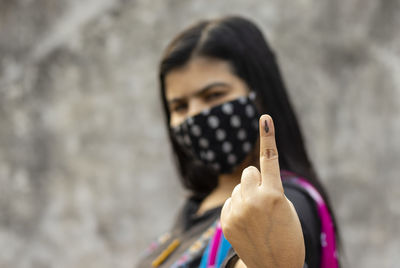 Selective focus on ink-marked finger of an indian woman with safety face mask