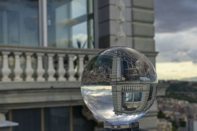 Close-up of crystal ball against building in city