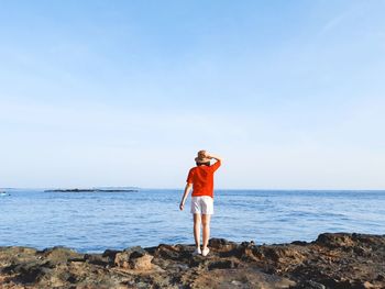 Full length of man standing on rock at beach against sky