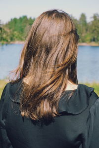 Rear view of woman standing against lake