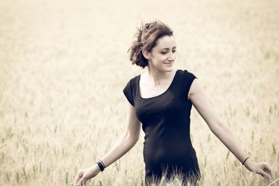 Smiling young woman standing on wheat field 