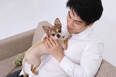 Man sitting with dog on sofa against white background