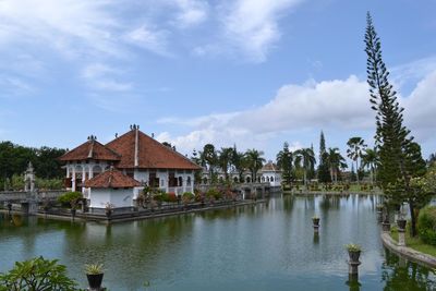 Houses by lake and buildings against sky