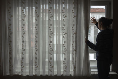 Side view of woman looking through window