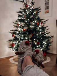 Low section of person wearing christmas tree on floor at home