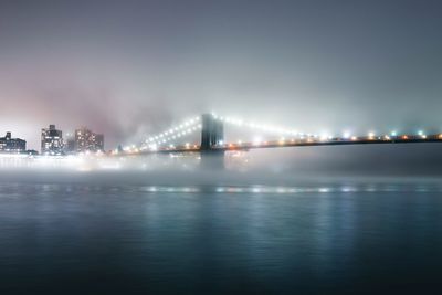 Illuminated brooklyn bridge over river at night