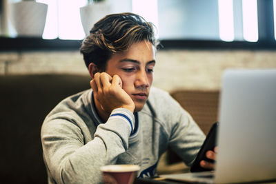 Young man using mobile phone while sitting on table
