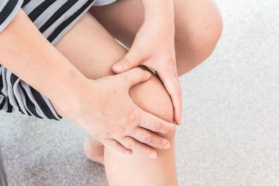 Midsection of woman touching knee while suffering from pain