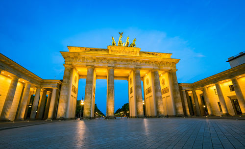 Brandenburg gate against clear blue sky in city at dusk