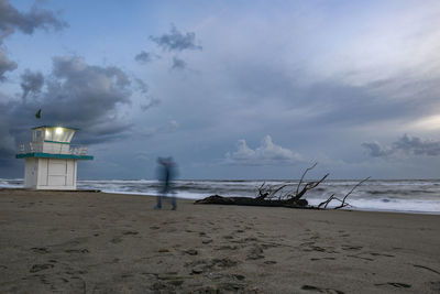 Lighthouse on beach against sky