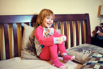 Happy girl with toy on bed at home