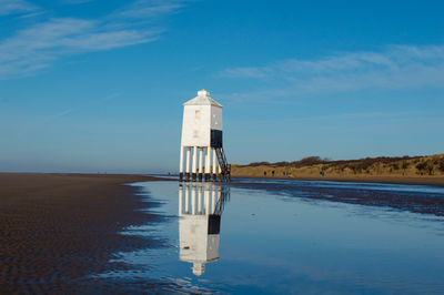 View of tower on beach against blue sky