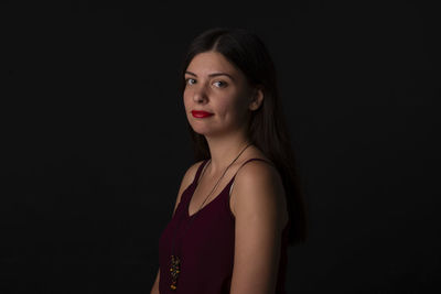 Portrait of smiling young woman against black background