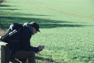 High angle view of man using mobile phone while sitting on seat in park