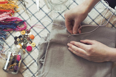 High angle view of woman stitching fabric on table at home