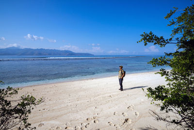 Man standing on sand at beach against sky