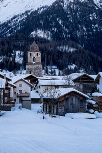 Snow covered houses by buildings against mountain