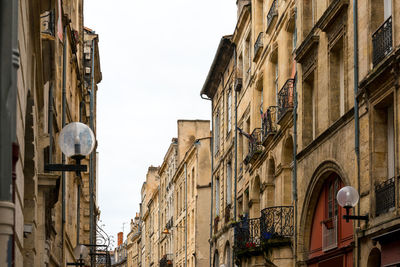 Low angle view of gas lights mounted on buildings in city