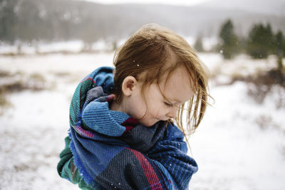 Happy girl wrapped in blanket during winter