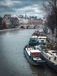 Bridge over river by buildings against sky